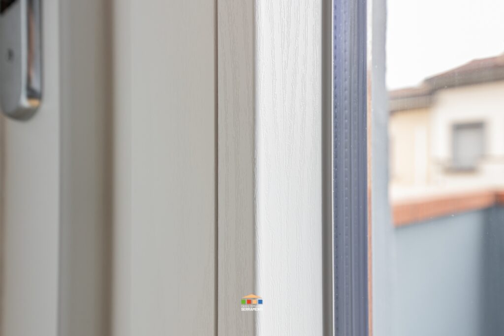 Dettaglio di un infisso in PVC bicolore con doppio vetro: lato interno bianco effetto legno, lato esterno effetto legno rovere dorato nel rispetto delle norme condominiali